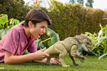 Child playing with toy dinosaurs on grass
